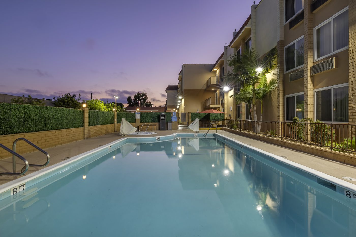 Hotel pool at dusk with palm trees and lit building